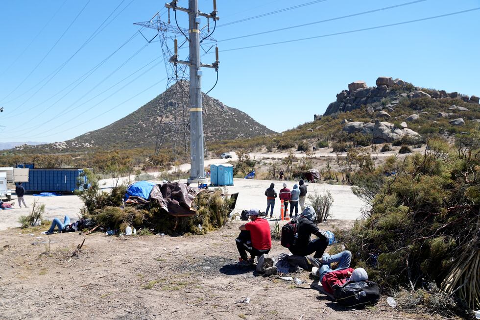 Asylum-seekers wait in a makeshift camp after crossing the nearby border with Mexico,...