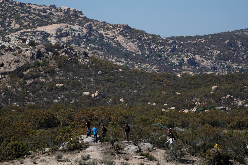 Asylum-seekers wait in a makeshift camp after crossing the nearby border with Mexico,...