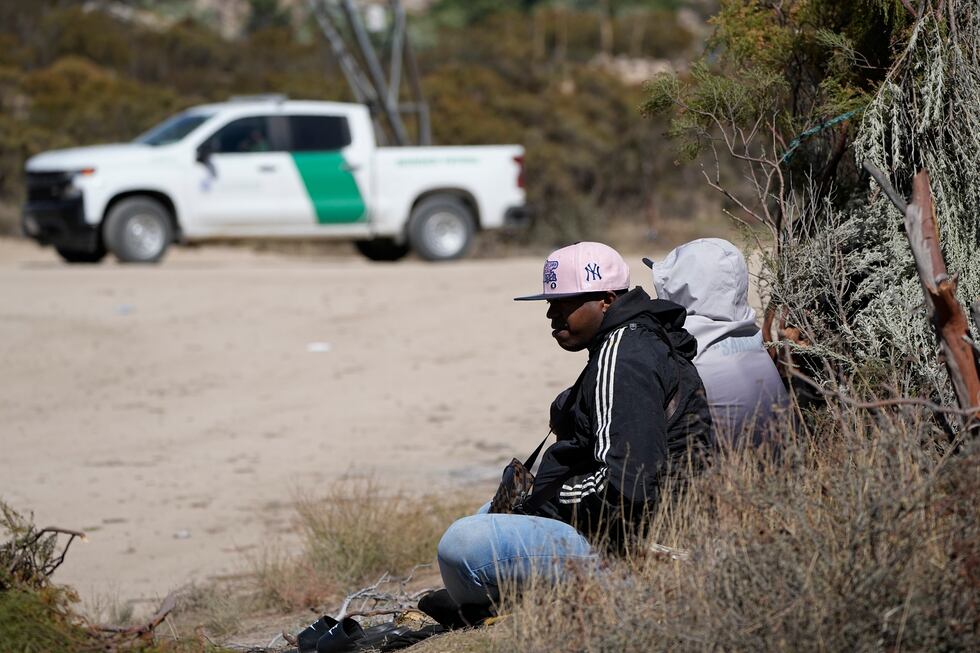 Asylum-seekers wait in a makeshift camp after crossing the nearby border with Mexico,...
