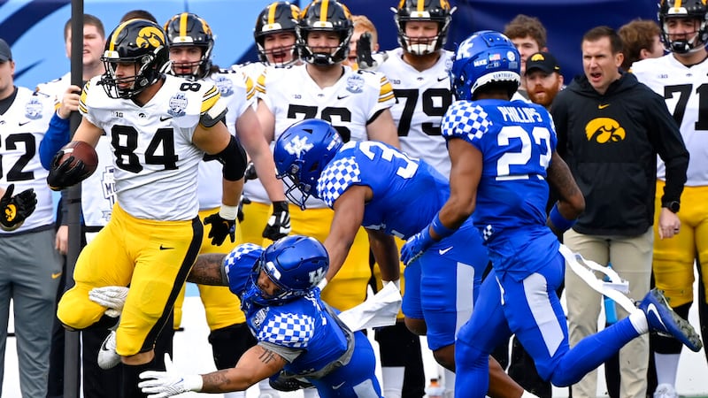 Iowa tight end Sam LaPorta (84) carries the ball after catching a pass as Kentucky defenders...