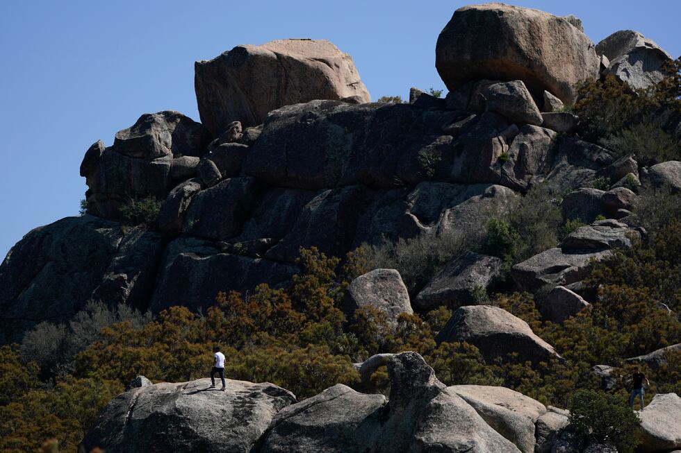 An asylum-seeker tries to find cell phone signal by climbing up rocks after crossing the...