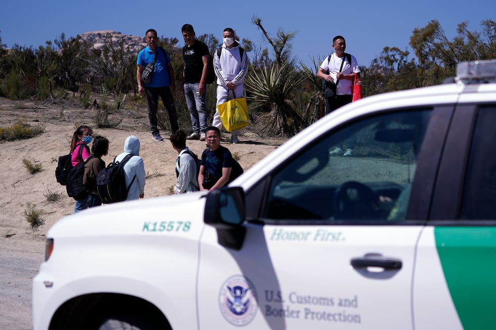 Asylum-seekers wait in a makeshift camp after crossing the nearby border with Mexico,...
