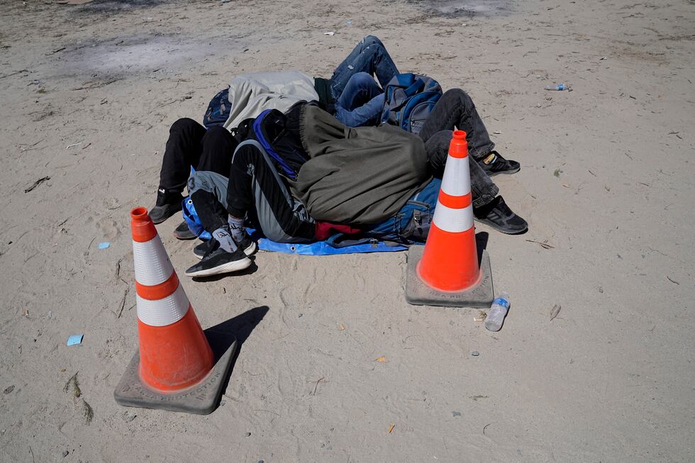 Asylum-seekers wait in a makeshift camp after crossing the nearby border with Mexico,...