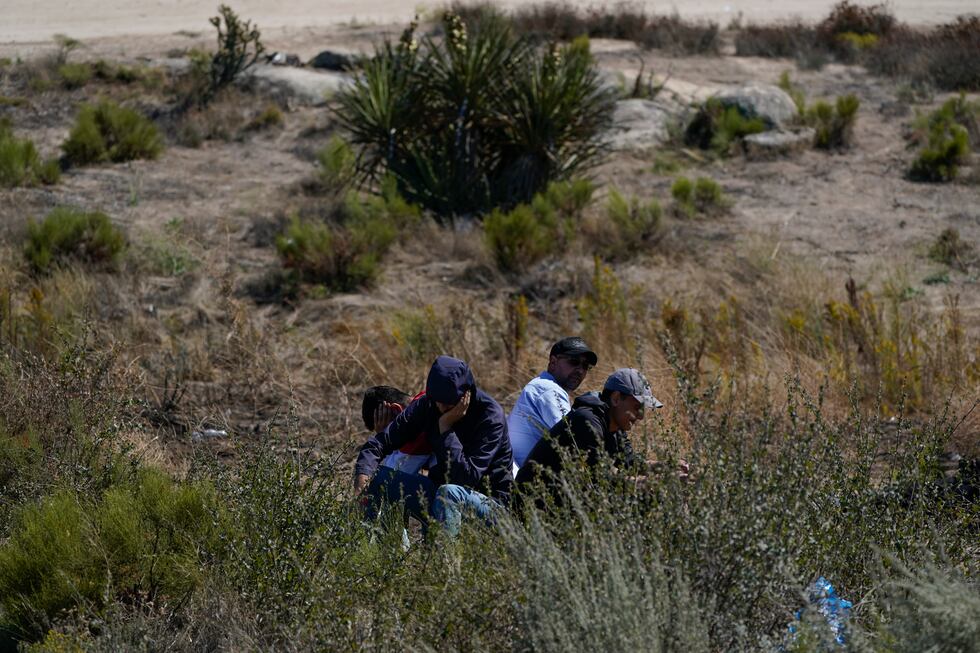 Asylum-seekers wait in a makeshift camp after crossing the nearby border with Mexico,...